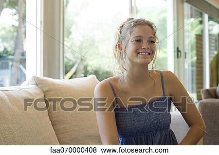 Woman sitting on sofa, smiling View Large Photo Image Stock Photo - Woman sitting on sofa, smiling. Fotosearch