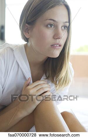 Woman touching knee, looking away in thought View Large Photo Image Stock Photo - Woman touching knee, looking away in thought. Fotosearch