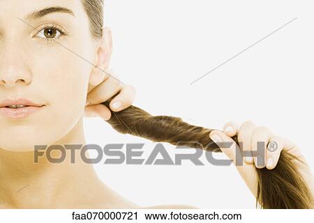 Stock Image - Woman twisting hair, close-up, cropped. Fotosearch