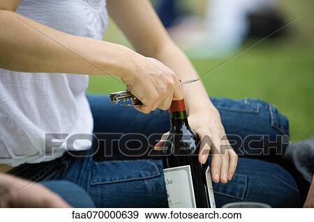 Woman uncorking bottle of wine outdoors, cropped View Large Photo Image Stock Photo - Woman uncorking bottle of wine outdoors, cropped. Fotosearch