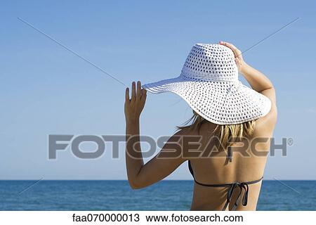 Woman wearing sun hat at the beach, rear view View Large Photo Image Stock Image - Woman wearing sun hat at the beach, rear view. Fotosearch