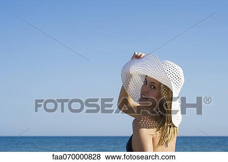 Woman wearing sun hat at the beach, looking over shoulder, portrait View Large Photo Image Stock Photo - Woman wearing sun hat at the beach, looking over shoulder, portrait. Fotosearch