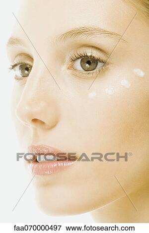Stock Photo - Woman with dots of undereye cream applied beneath eye, close-up of face. Fotosearch