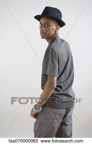Young man in hat looking over shoulder, portrait View Large Photo Image Stock Image - Young man in hat looking over shoulder, portrait. Fotosearch
