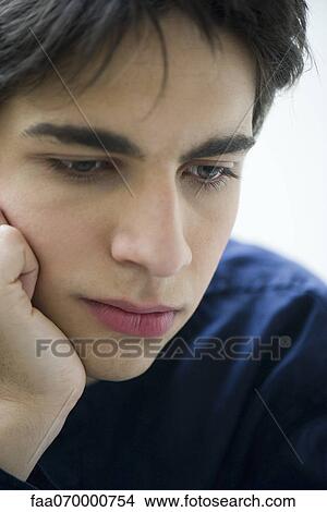 Young man looking down in thought, portrait View Large Photo Image Picture - Young man looking down in thought, portrait. Fotosearch