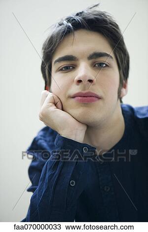 Stock Image - Young man with hand under chin, portrait. Fotosearch