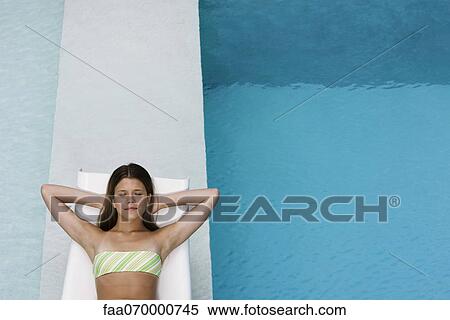 Young woman contentedly reclining on poolside deckchair View Large Photo Image Stock Photography - Young woman contentedly reclining on poolside deckchair. Fotosearch