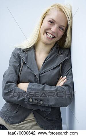 Young woman leaning against wall, smiling, portrait View Large Photo Image Stock Image - Young woman leaning against wall, smiling, portrait. Fotosearch