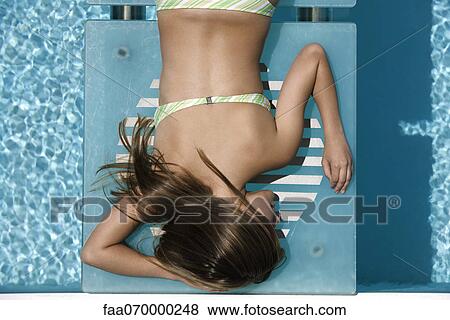 Young woman sunbathing by pool View Large Photo Image Stock Photo - Young woman sunbathing by pool. Fotosearch