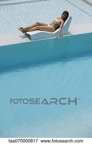 Young woman sunbathing by pool View Large Photo Image Stock Photo - Young woman sunbathing by pool. Fotosearch