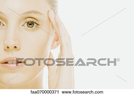 Young woman with hand held to side of head, close-up View Large Photo Image Stock Image - Young woman with hand held to side of head, close-up. Fotosearch