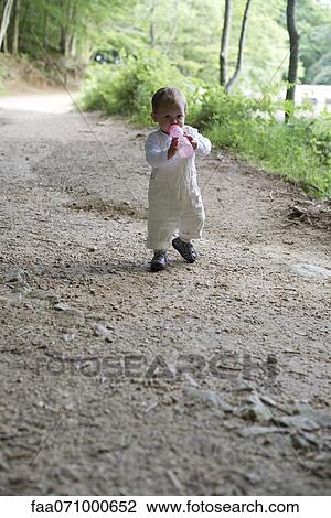 Baby girl holding baby bottle in woods View Large Photo Image Stock Image - Baby girl holding baby bottle in woods. Fotosearch