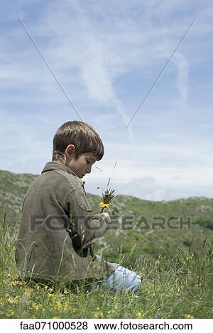 Boy kneeling on meadow with flowers in hand View Large Photo Image Stock Photo - Boy kneeling on meadow with flowers in hand. Fotosearch