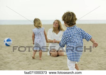 Boy playing on beach, family in background View Large Photo Image Stock Image - Boy playing on beach, family in background. Fotosearch