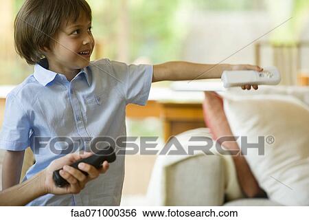 Stock Photograph - Boy playing video game using wireless controller. Fotosearch