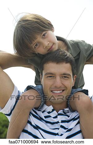 Boy riding on his father's shoulders, portrait View Large Photo Image Picture - Boy riding on his father's shoulders, portrait. Fotosearch