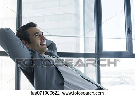 Business executive relaxing with hands behind head View Large Photo Image Stock Image - Business executive relaxing with hands behind head. Fotosearch
