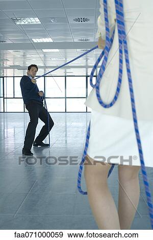 Businessman playing tug of war, focus on background View Large Photo Image Stock Photo - Businessman playing tug of war, focus on background. Fotosearch