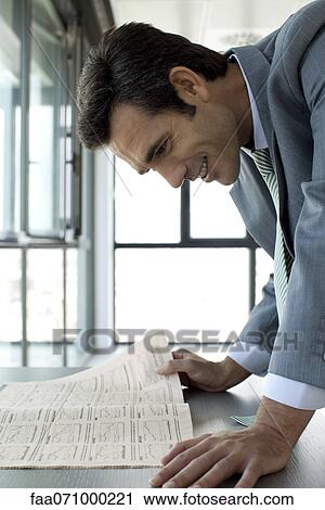 Businessman reading finance section of newspaper, smiling View Large Photo Image Stock Image - Businessman reading finance section of newspaper, smiling. Fotosearch