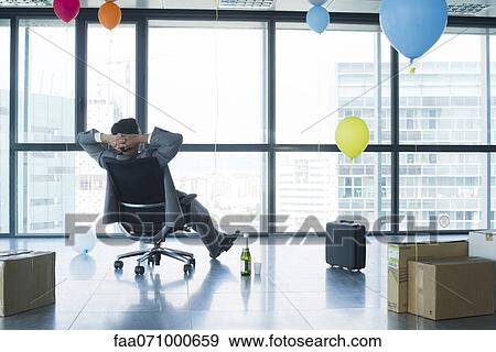 Businessman sitting in new office with balloons and boxes View Large Photo Image Stock Photo - Businessman sitting in new office with balloons and boxes. Fotosearch