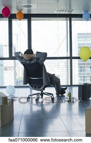 Businessman sitting in new office with balloons and boxes View Large Photo Image Stock Photograph - Businessman sitting in new office with balloons and boxes. Fotosearch