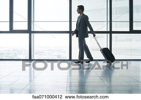 Businessman with wheeled suitcase View Large Photo Image Stock Image - Businessman with wheeled suitcase. Fotosearch