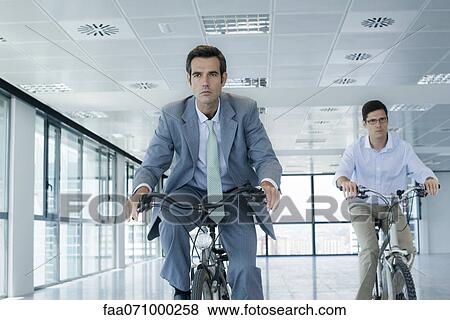 Businessmen riding bicycles indoors View Large Photo Image Stock Photo - Businessmen riding bicycles indoors. Fotosearch