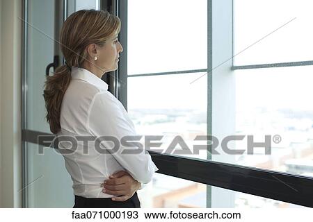 Stock Image - Businesswoman looking out of window. Fotosearch