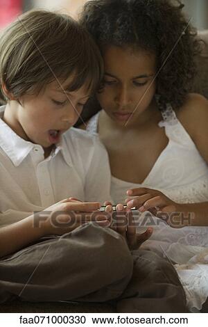 Stock Image - Children looking at cell phone together. Fotosearch