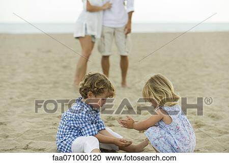 Stock Image - Children playing in sand at the beach. Fotosearch