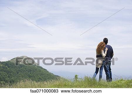 Stock Image - Couple enjoying scenic mountain view, rear view. Fotosearch