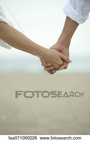 Couple holding hands outdoors, cropped View Large Photo Image Stock Photograph - Couple holding hands outdoors, cropped. Fotosearch
