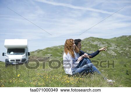 Couple sitting on meadow View Large Photo Image Stock Photo - Couple sitting on meadow. Fotosearch