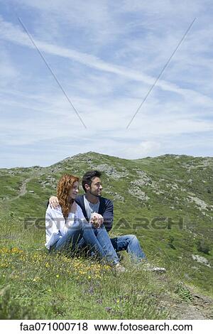 Couple sitting on meadow View Large Photo Image Stock Photo - Couple sitting on meadow. Fotosearch