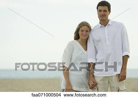 Picture - Couple standing together at the beach. Fotosearch