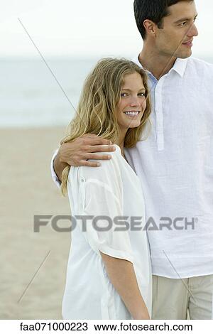 Stock Image - Couple standing together at the beach. Fotosearch