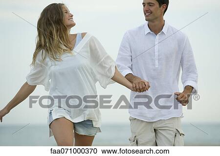 Couple walking hand in hand at the beach View Large Photo Image Stock Image - Couple walking hand in hand at the beach. Fotosearch