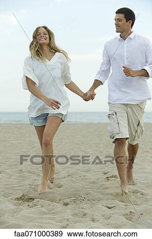 Couple walking hand in hand at the beach View Large Photo Image Stock Photo - Couple walking hand in hand at the beach. Fotosearch