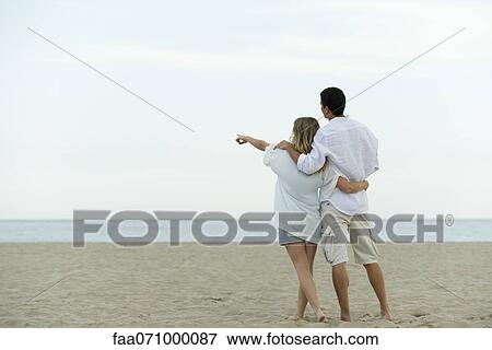 Couple walking together at the beach, woman pointing at sea View Large Photo Image Stock Photo - Couple walking together at the beach, woman pointing at sea. Fotosearch