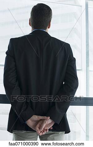 Stock Image - Executive looking out window, rear view. Fotosearch