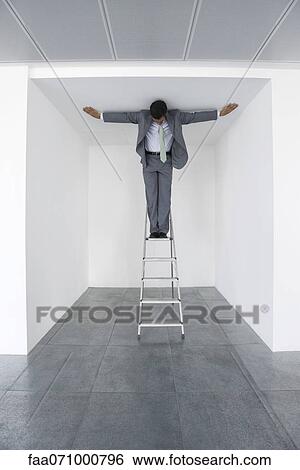 Executive standing on stepladder, arms outstretched on ceiling View Large Photo Image Stock Photograph - Executive standing on stepladder, arms outstretched on ceiling. Fotosearch