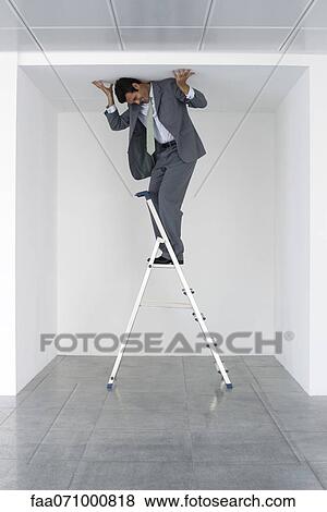 Executive standing on stepladder, pushing ceiling View Large Photo Image Stock Photo - Executive standing on stepladder, pushing ceiling. Fotosearch