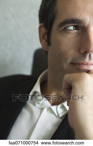 Picture - Executive with hand under chin, close-up, cropped. Fotosearch