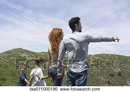 Stock Image - Family enjoying scenic mountain view, rear view. Fotosearch