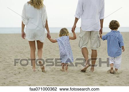 Stock Image - Family walking hand in hand at the beach. Fotosearch