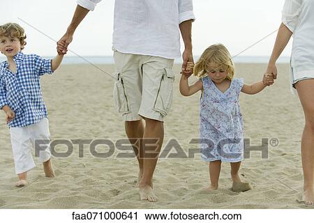 Family walking hand in hand at the beach, cropped View Large Photo Image Stock Image - Family walking hand in hand at the beach, cropped. Fotosearch