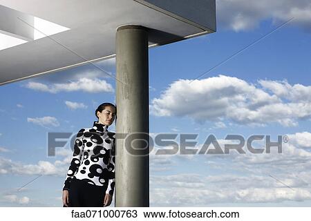 Fashionably dressed young woman leaning against portico column View Large Photo Image Stock Image - Fashionably dressed young woman leaning against portico column. Fotosearch