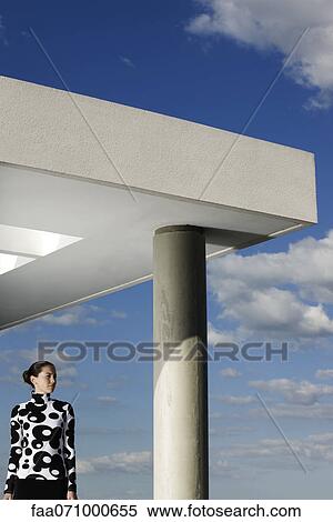 Fashionably dressed young woman contemplating view from portico View Large Photo Image Stock Photography - Fashionably dressed young woman contemplating view from portico. Fotosearch