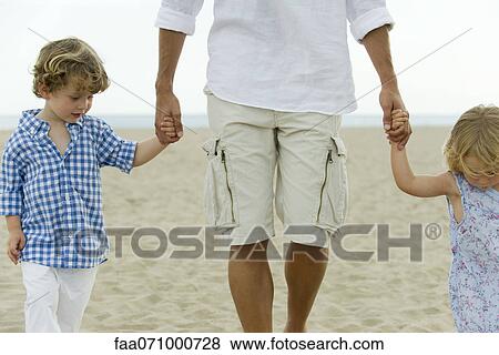 Father and children walking hand in hand on beach, cropped View Large Photo Image Stock Photo - Father and children walking hand in hand on beach, cropped. Fotosearch