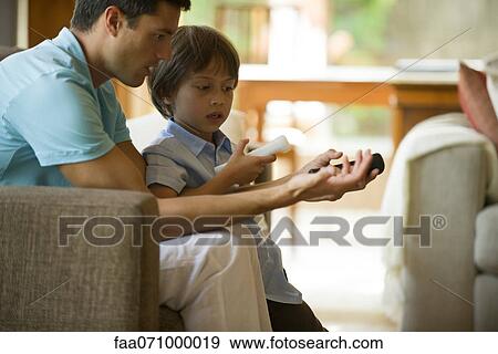 Father and son playing video game using wireless controllers View Large Photo Image Stock Photo - Father and son playing video game using wireless controllers. Fotosearch
